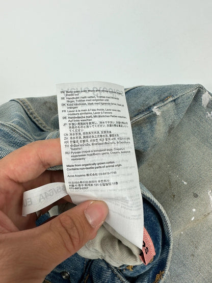 Acne Studios blue and white baggy jeans with intentional paint splatters and non-stretch denim.