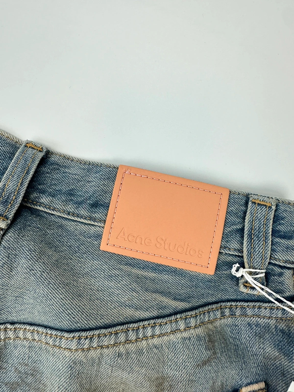Acne Studios blue and white baggy jeans with intentional paint splatters and non-stretch denim.