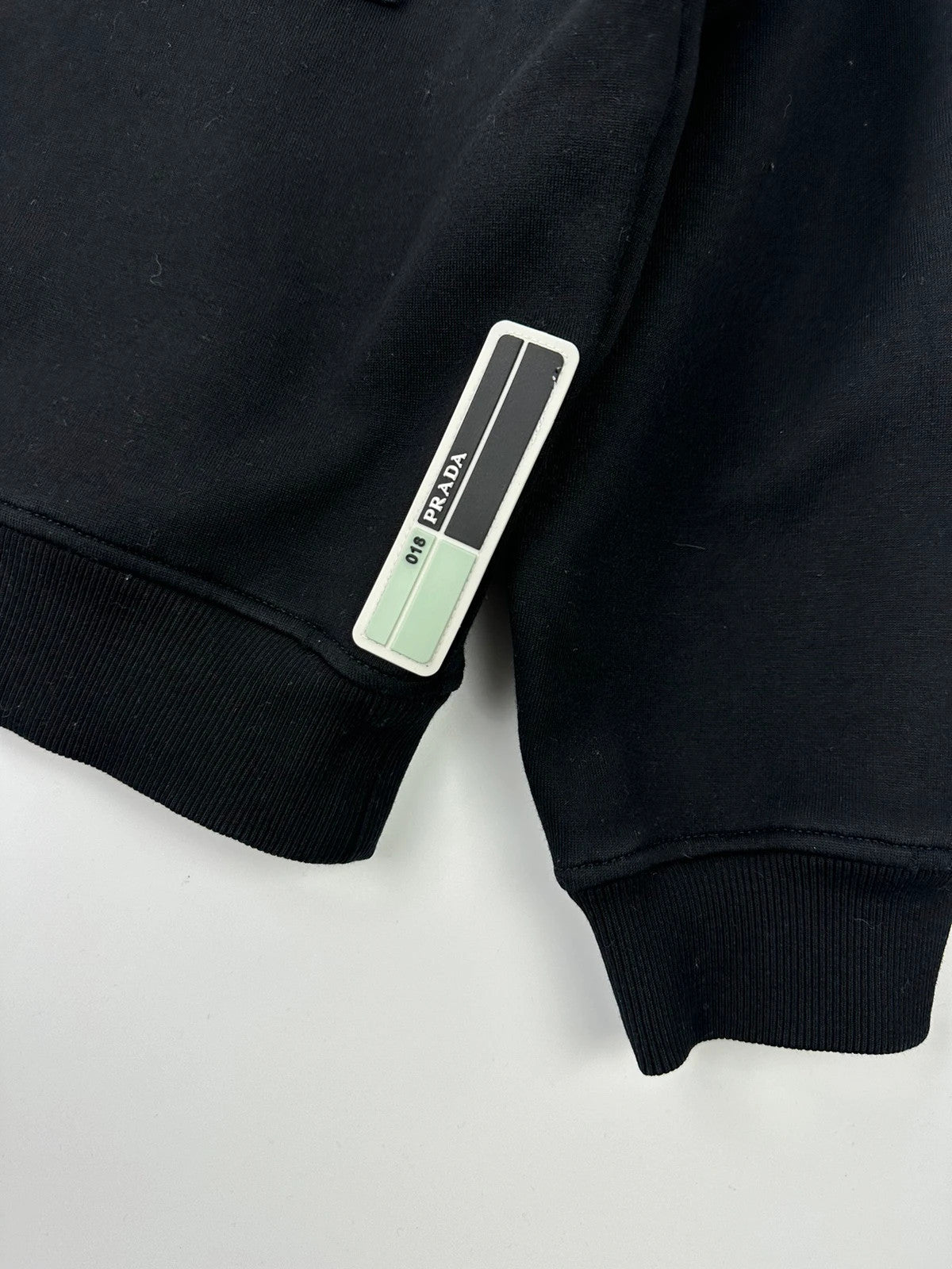 Prada black crop sweater with front pockets and logo detail, boxy fit.
