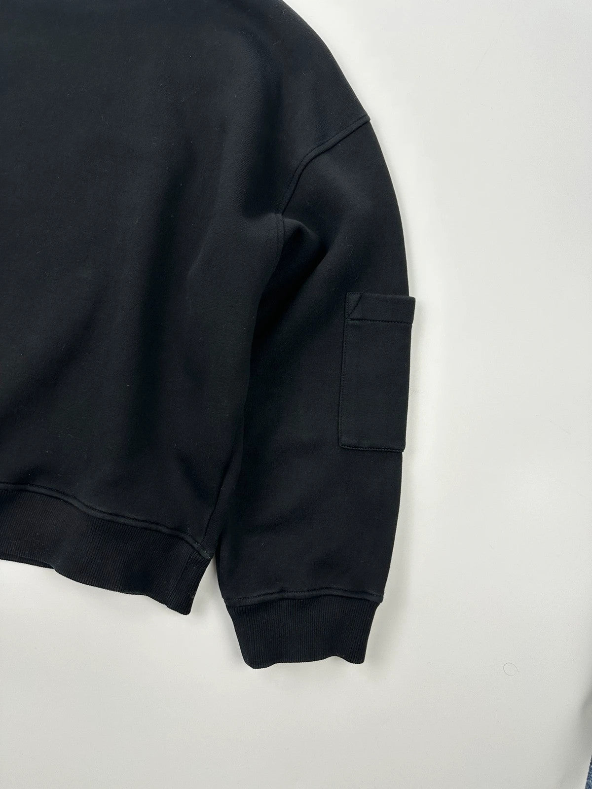 Prada black crop sweater with front pockets and logo detail, boxy fit.