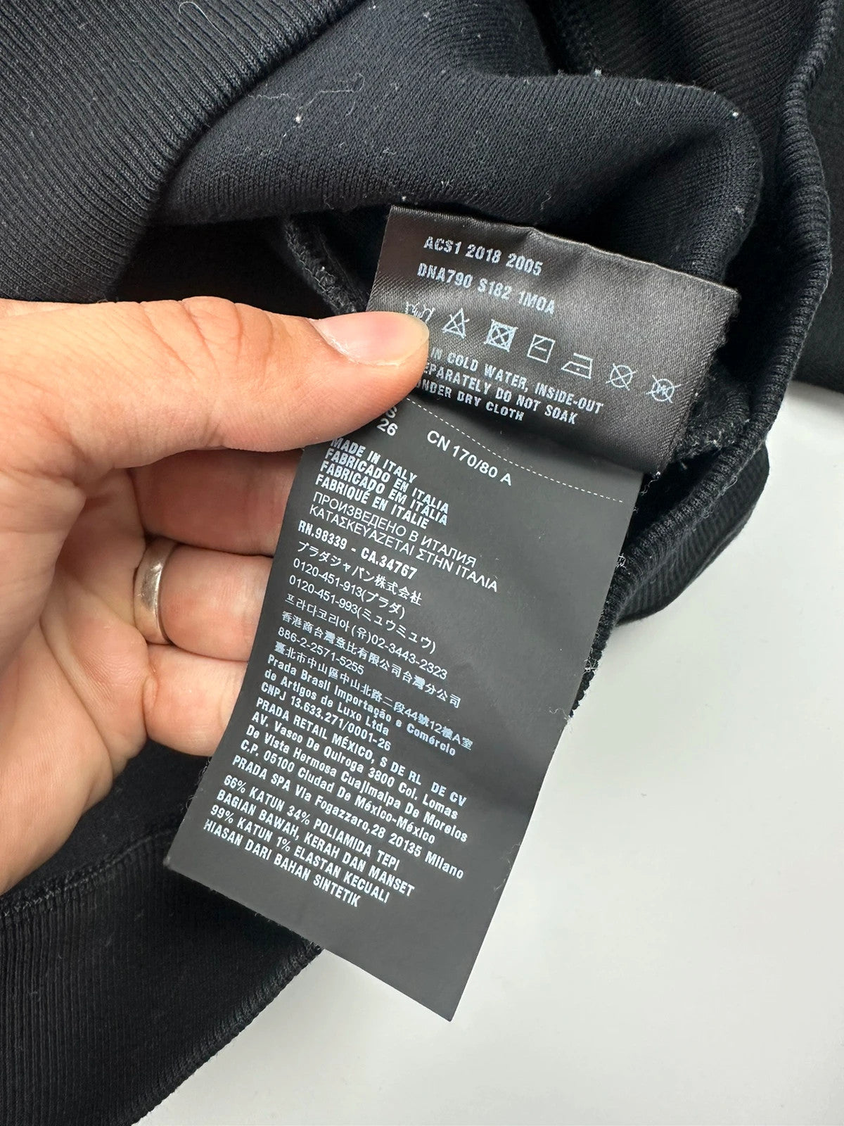 Prada black crop sweater with front pockets and logo detail, boxy fit.