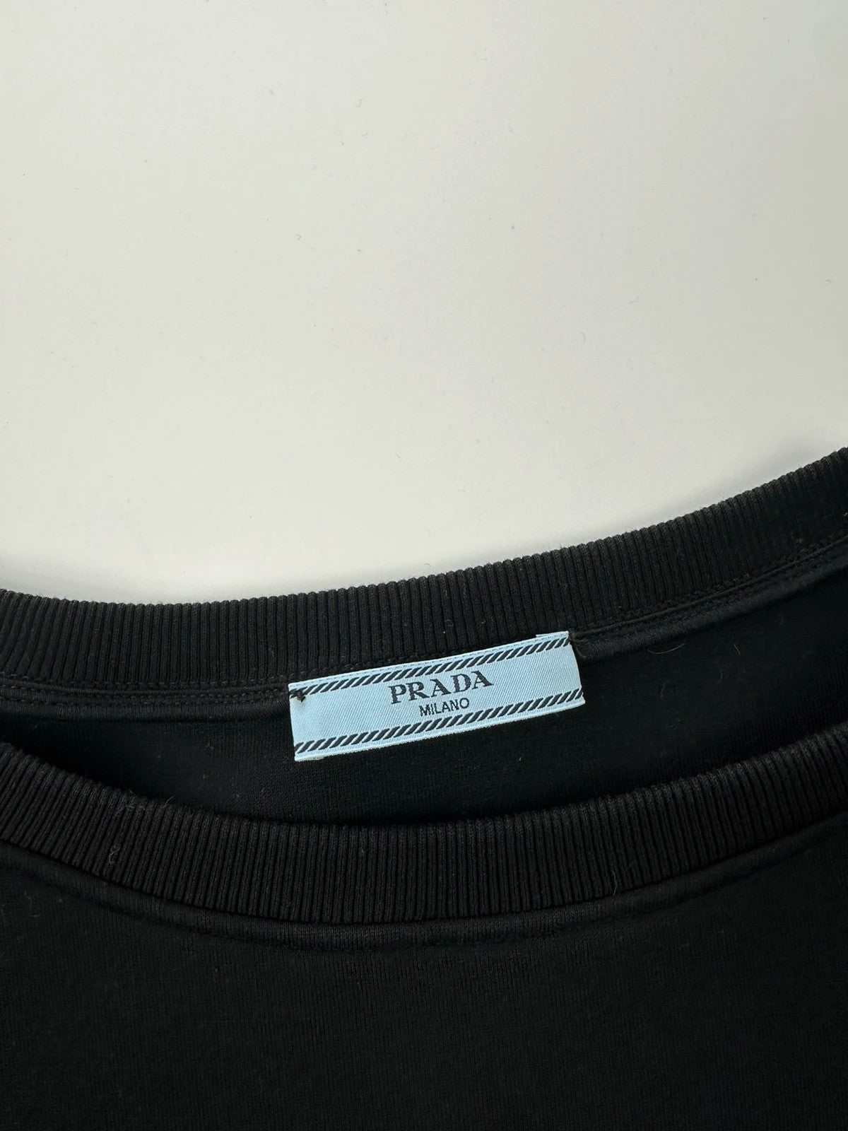 Prada black crop sweater with front pockets and logo detail, boxy fit.