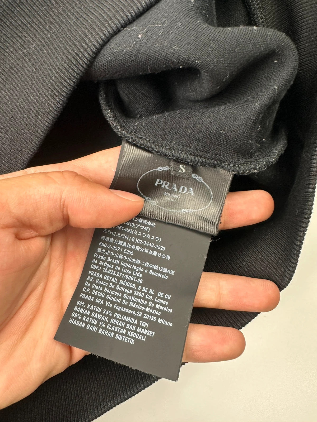 Prada black crop sweater with front pockets and logo detail, boxy fit.