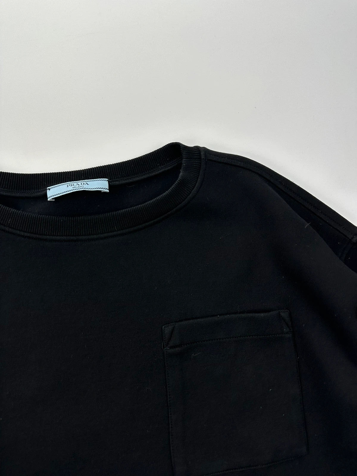 Prada black crop sweater with front pockets and logo detail, boxy fit.