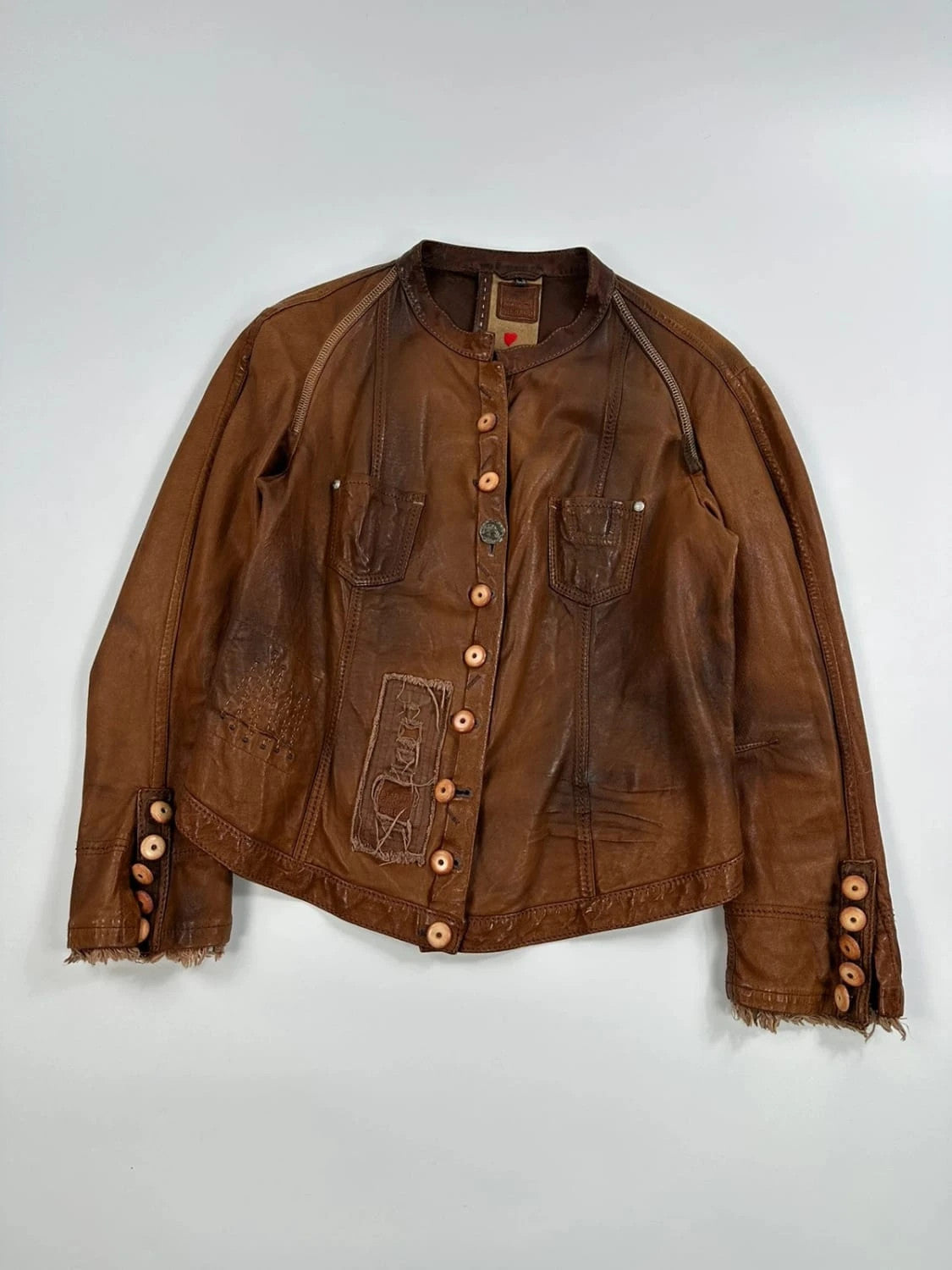 Marithé Francois Girbaud brown leather jacket with orange patches and logo details.