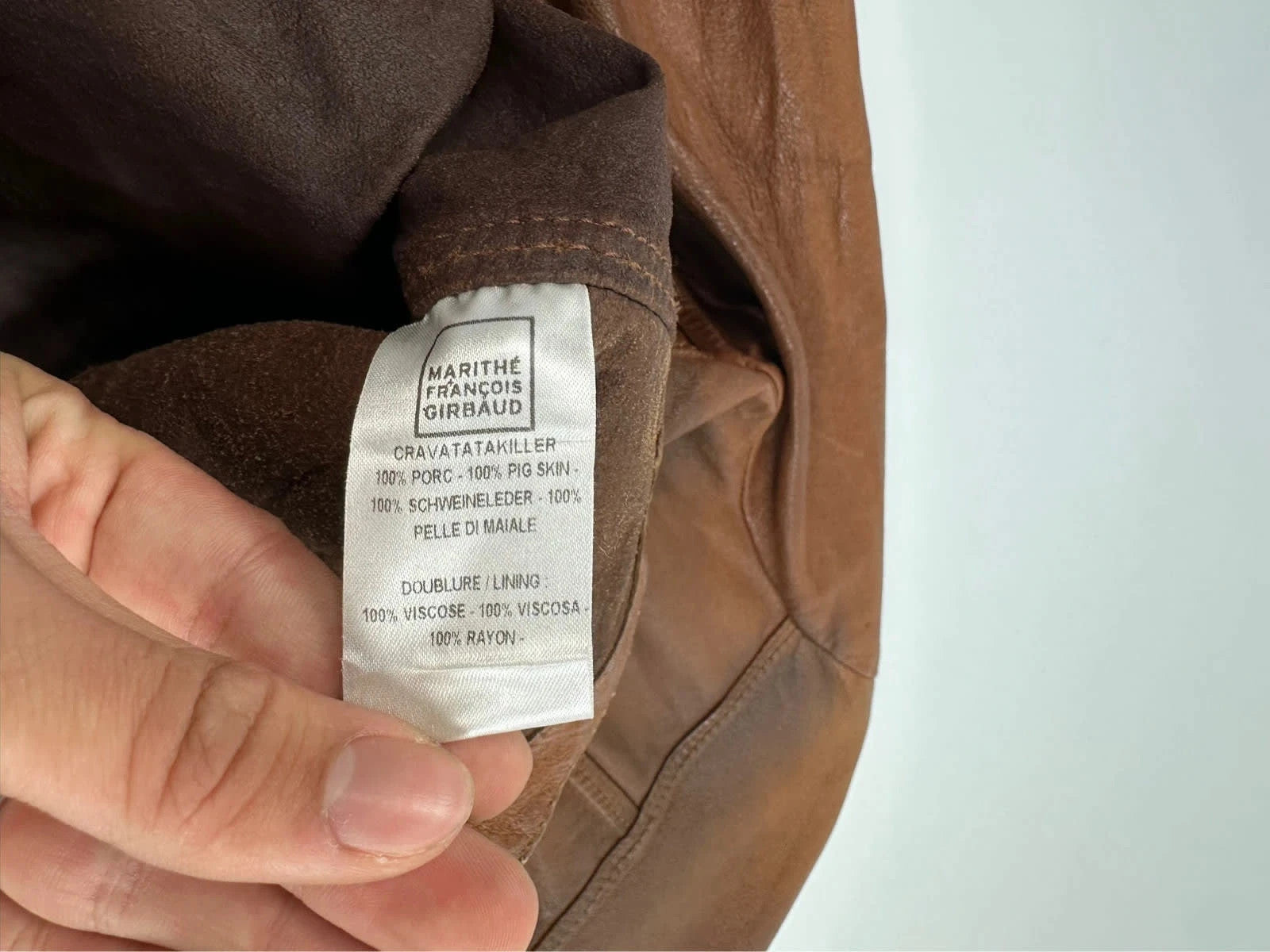 Marithé Francois Girbaud brown leather jacket with orange patches and logo details.