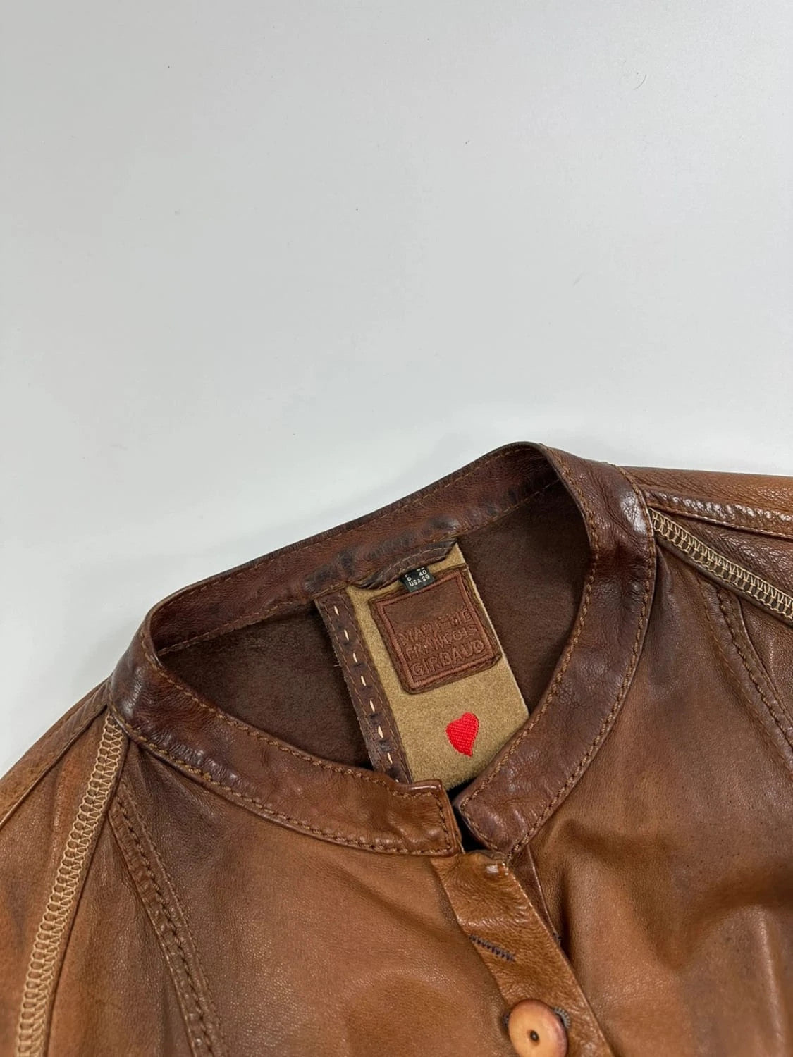 Marithé Francois Girbaud brown leather jacket with orange patches and logo details.