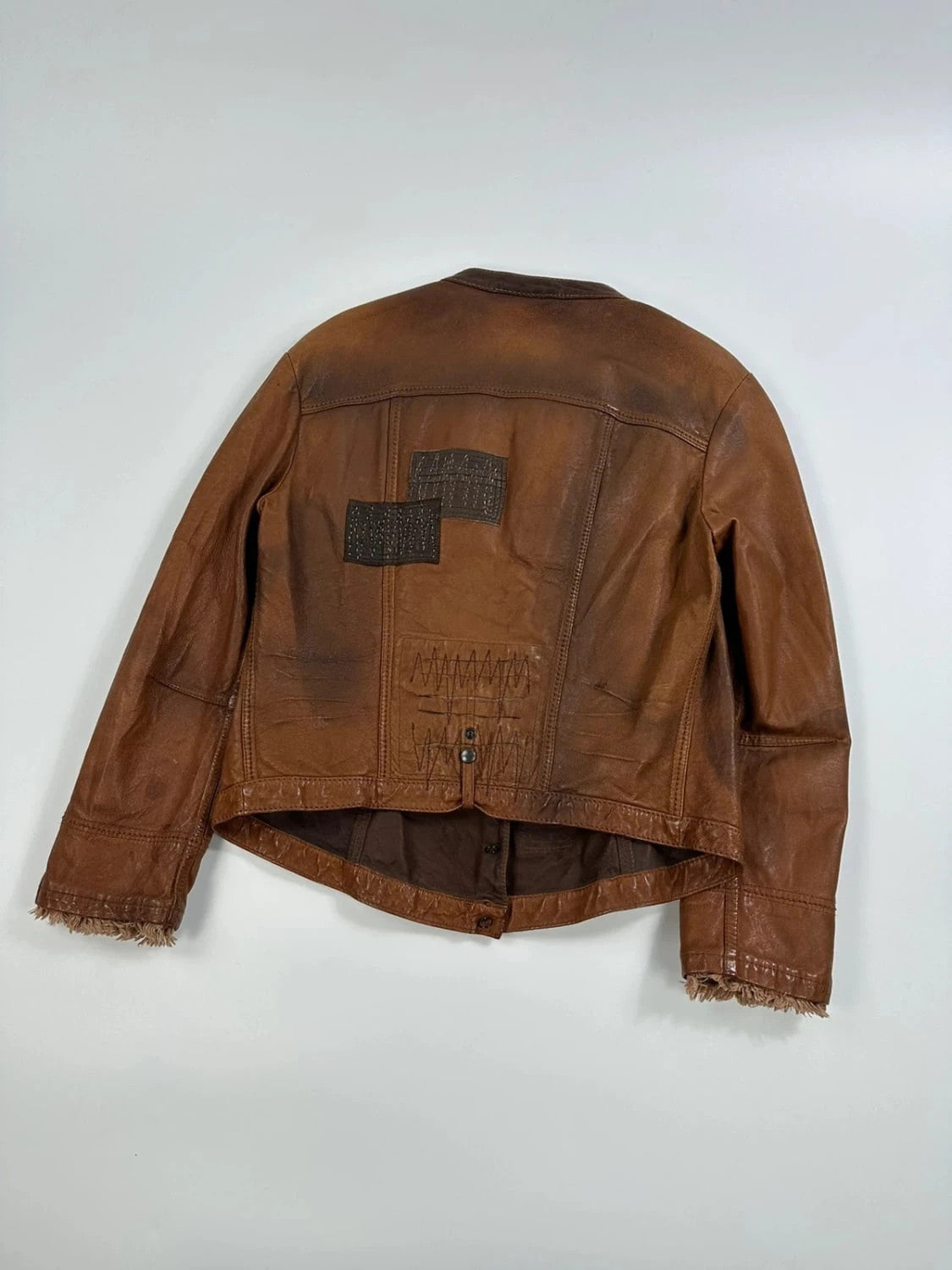 Marithé Francois Girbaud brown leather jacket with orange patches and logo details.