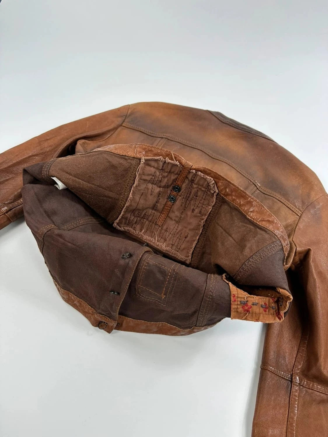 Marithé Francois Girbaud brown leather jacket with orange patches and logo details.