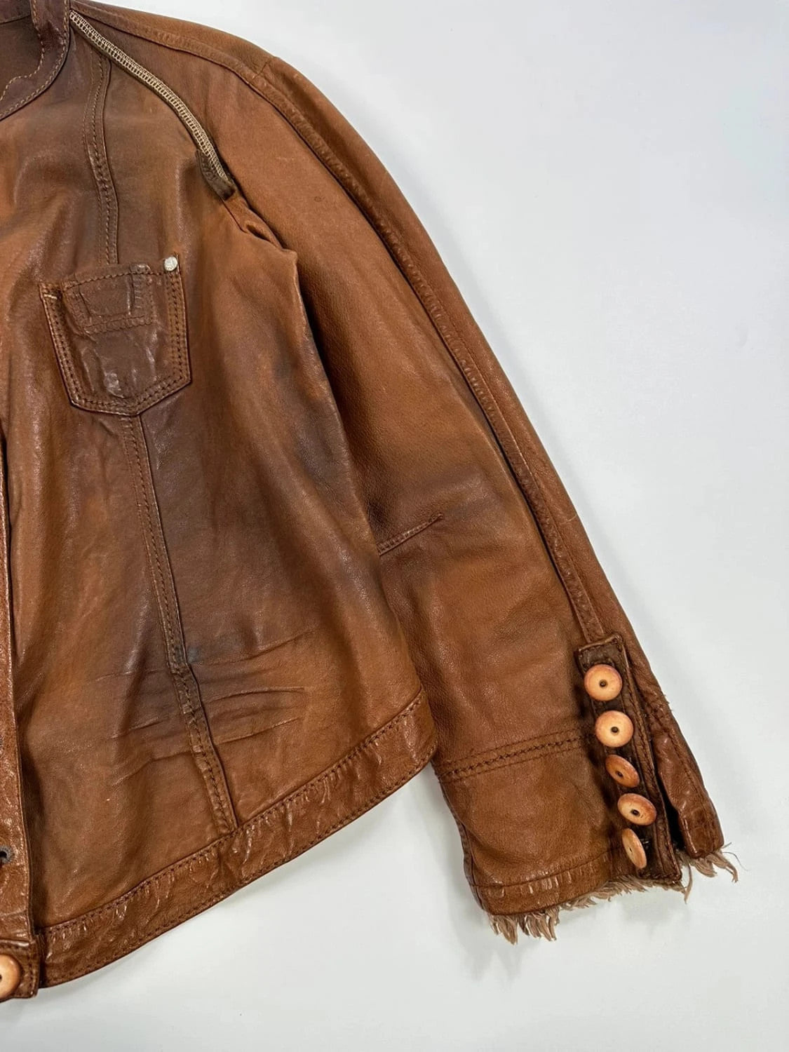 Marithé Francois Girbaud brown leather jacket with orange patches and logo details.