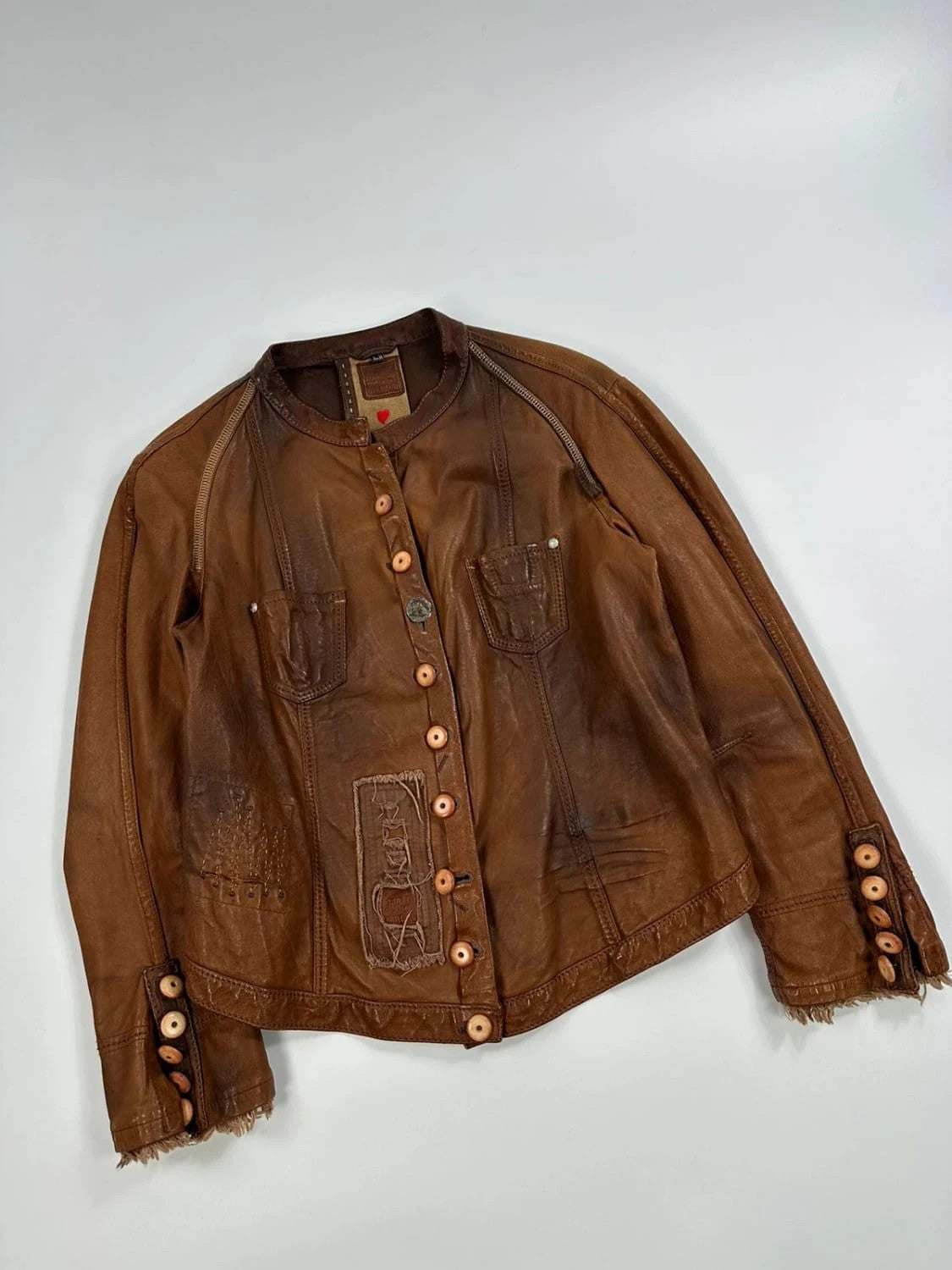Marithé Francois Girbaud brown leather jacket with orange patches and logo details.