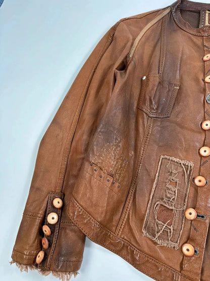 Marithé Francois Girbaud brown leather jacket with orange patches and logo details.