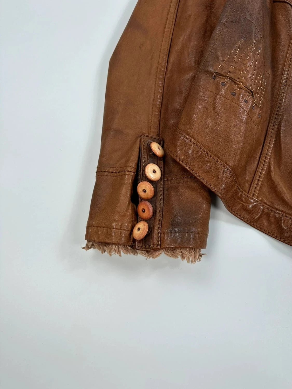 Marithé Francois Girbaud brown leather jacket with orange patches and logo details.