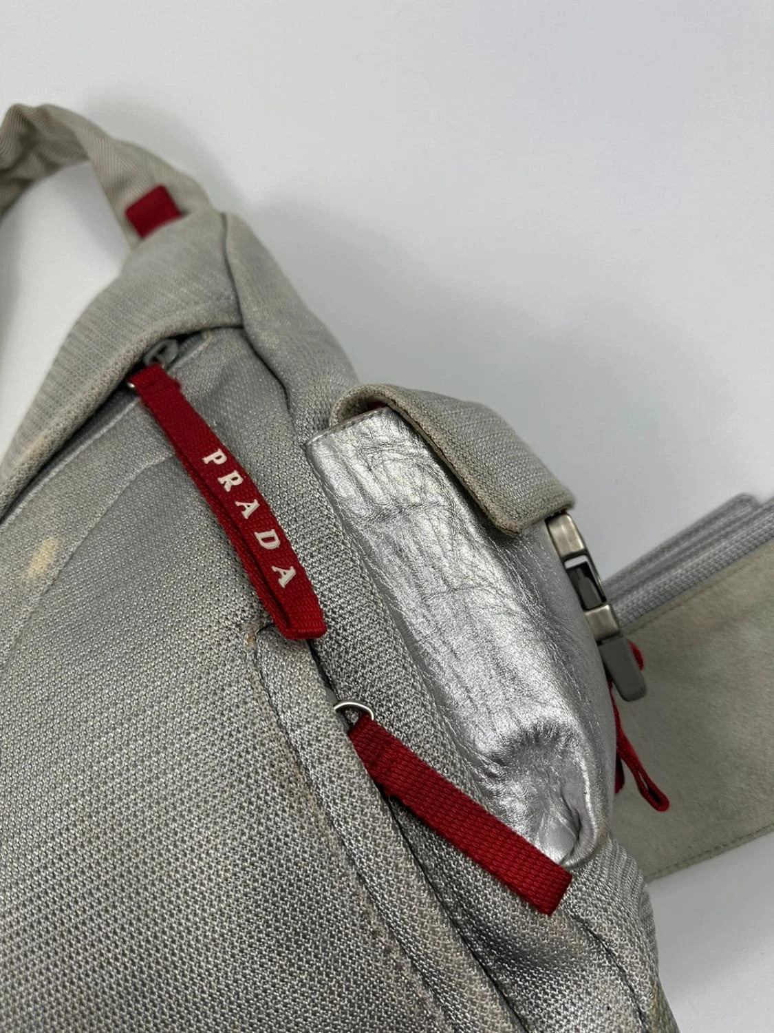 Prada grey sling bag with silver mesh and patent leather, featuring a collector's design.