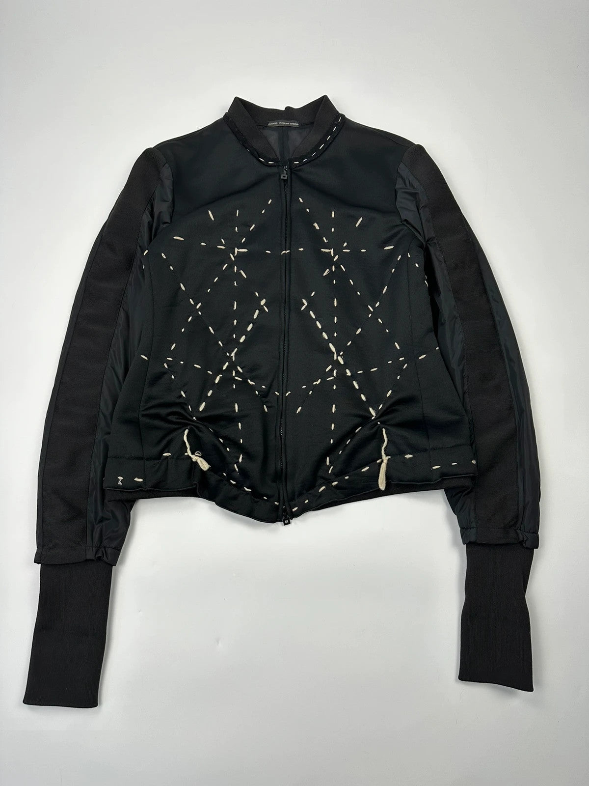 Marithé Francois Girbaud black coat with white utility stitching and logo details.
