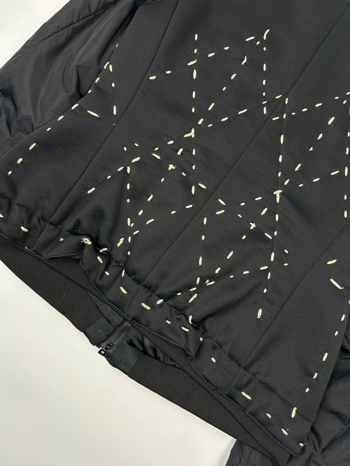 Marithé Francois Girbaud black coat with white utility stitching and logo details.