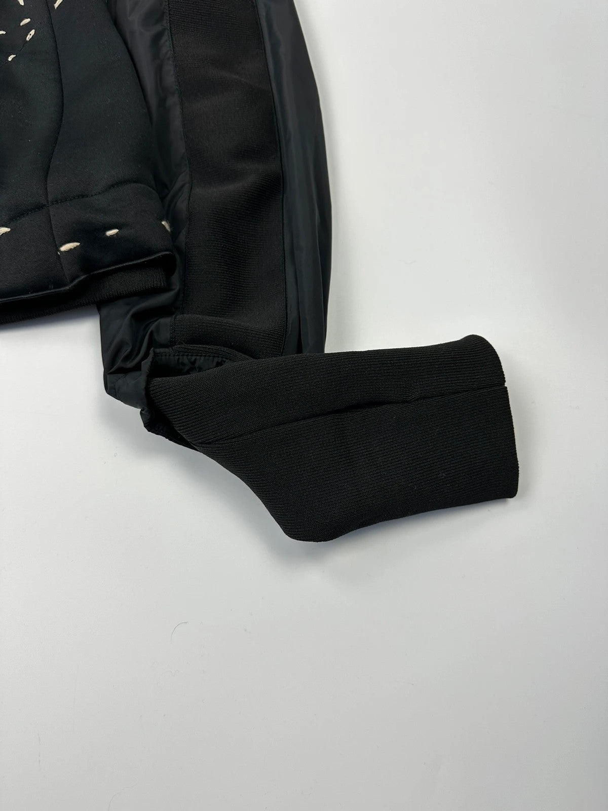 Marithé Francois Girbaud black coat with white utility stitching and logo details.
