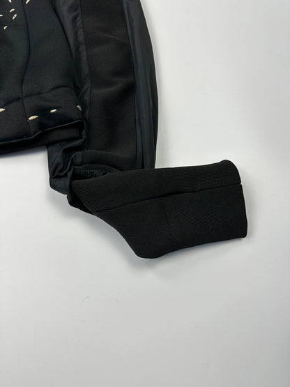 Marithé Francois Girbaud black coat with white utility stitching and logo details.