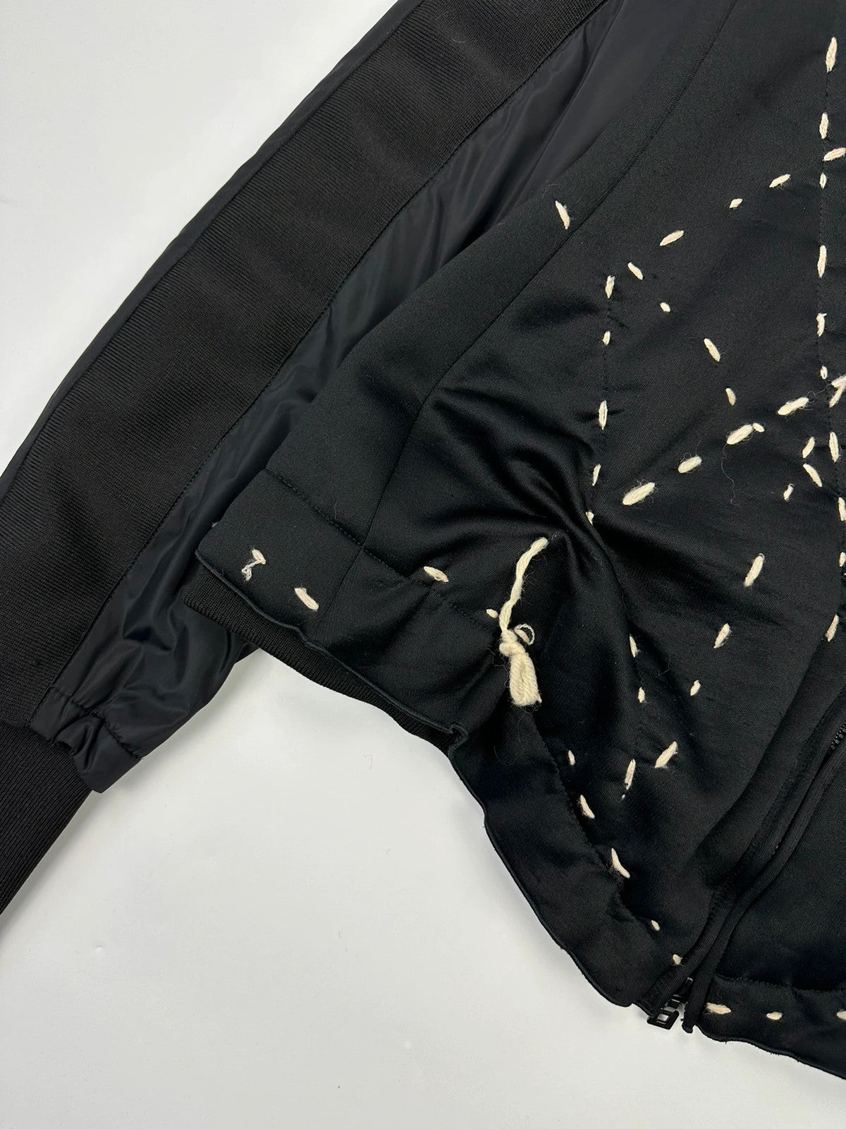 Marithé Francois Girbaud black coat with white utility stitching and logo details.