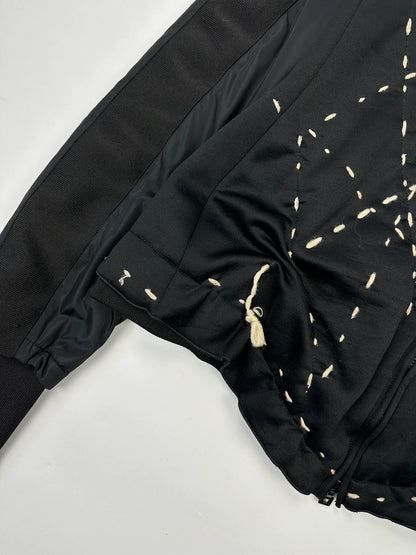 Marithé Francois Girbaud black coat with white utility stitching and logo details.