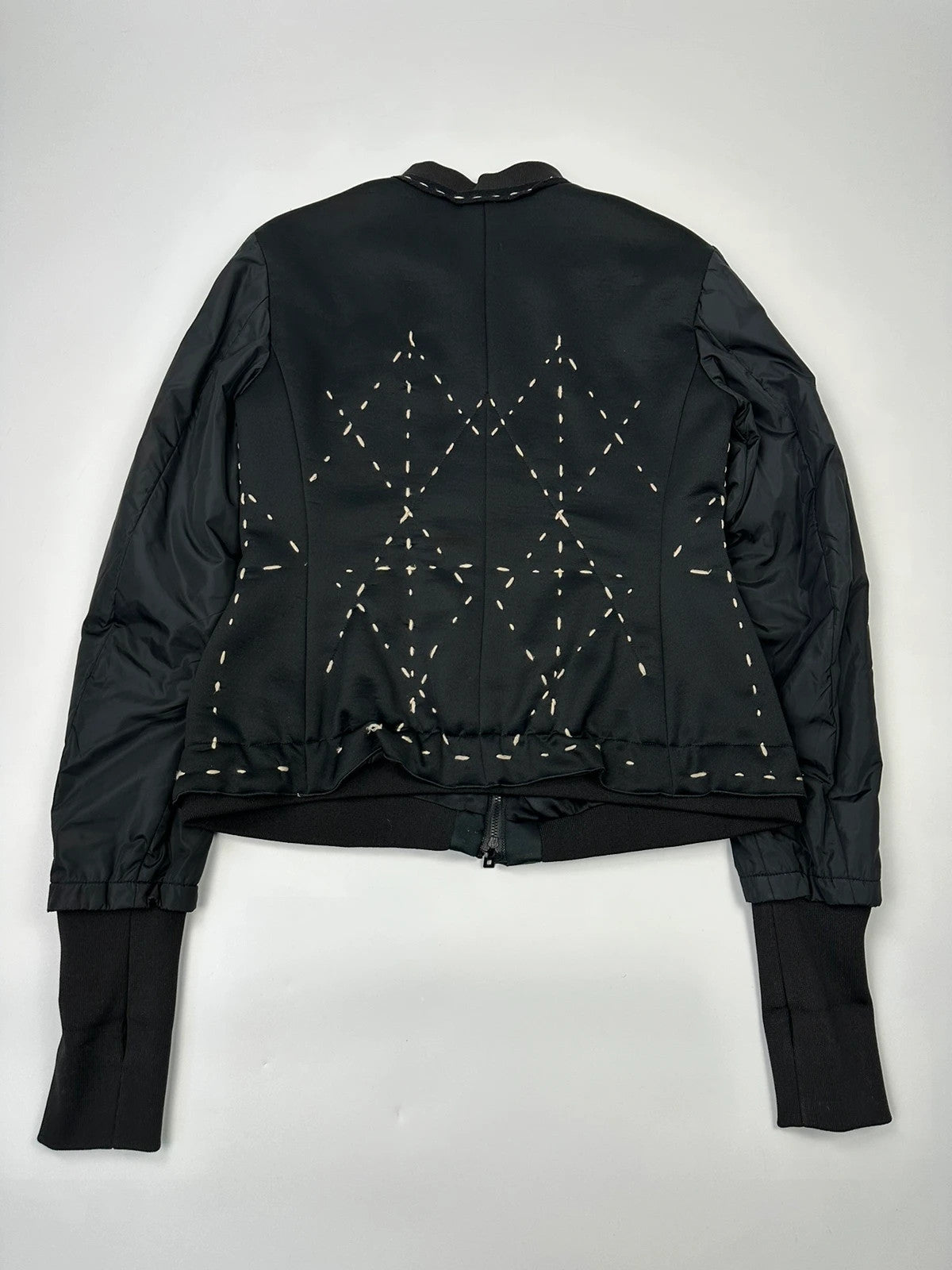 Marithé Francois Girbaud black coat with white utility stitching and logo details.