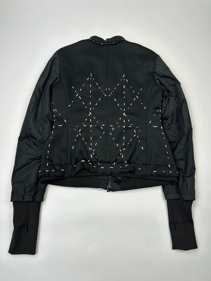 Marithé Francois Girbaud black coat with white utility stitching and logo details.