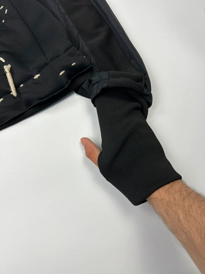 Marithé Francois Girbaud black coat with white utility stitching and logo details.