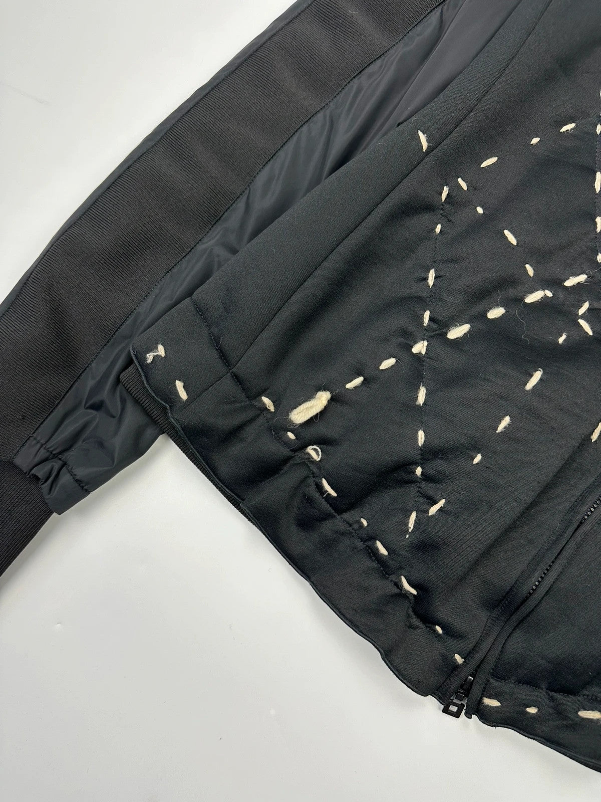 Marithé Francois Girbaud black coat with white utility stitching and logo details.