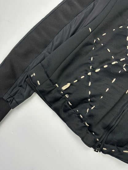 Marithé Francois Girbaud black coat with white utility stitching and logo details.