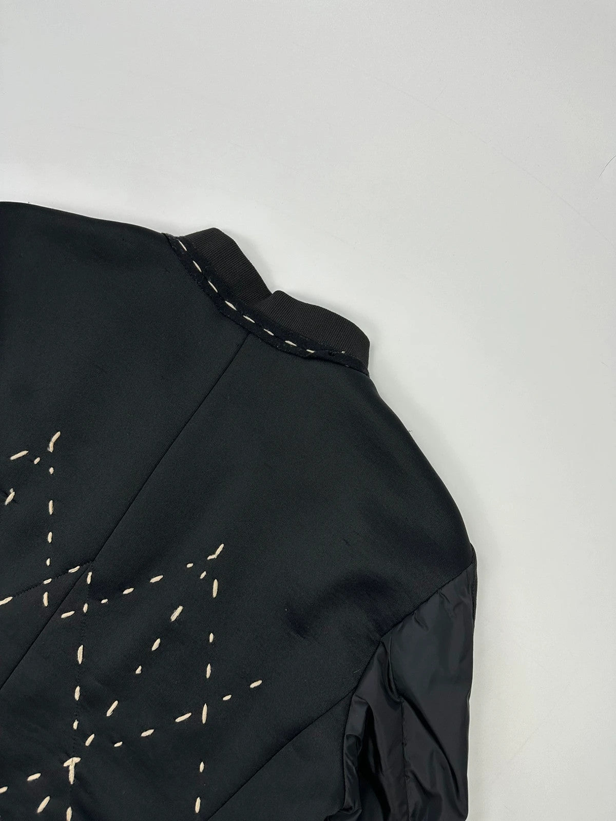 Marithé Francois Girbaud black coat with white utility stitching and logo details.