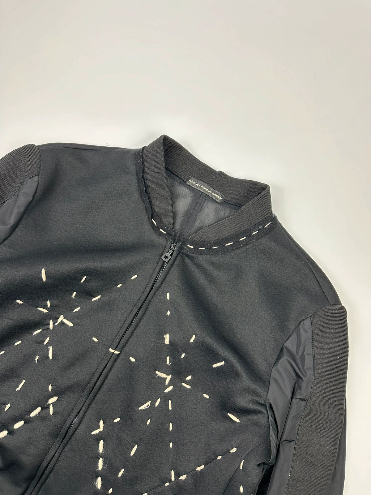 Marithé Francois Girbaud black coat with white utility stitching and logo details.