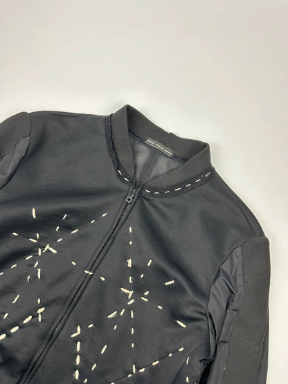Marithé Francois Girbaud black coat with white utility stitching and logo details.