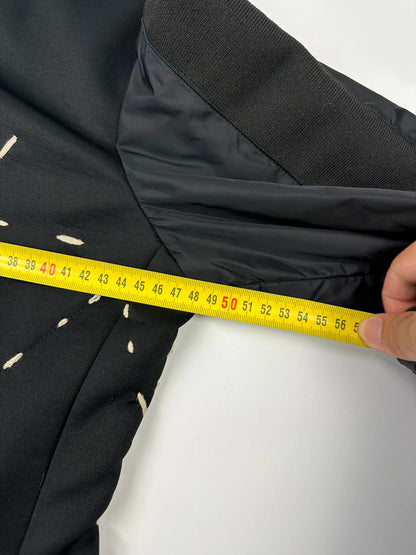 Marithé Francois Girbaud black coat with white utility stitching and logo details.