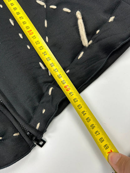 Marithé Francois Girbaud black coat with white utility stitching and logo details.
