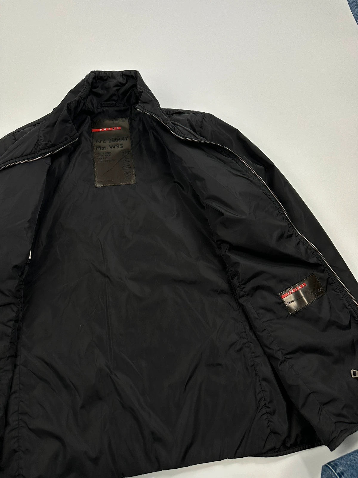 Prada black padded nylon jacket with double zip and minimalist design.