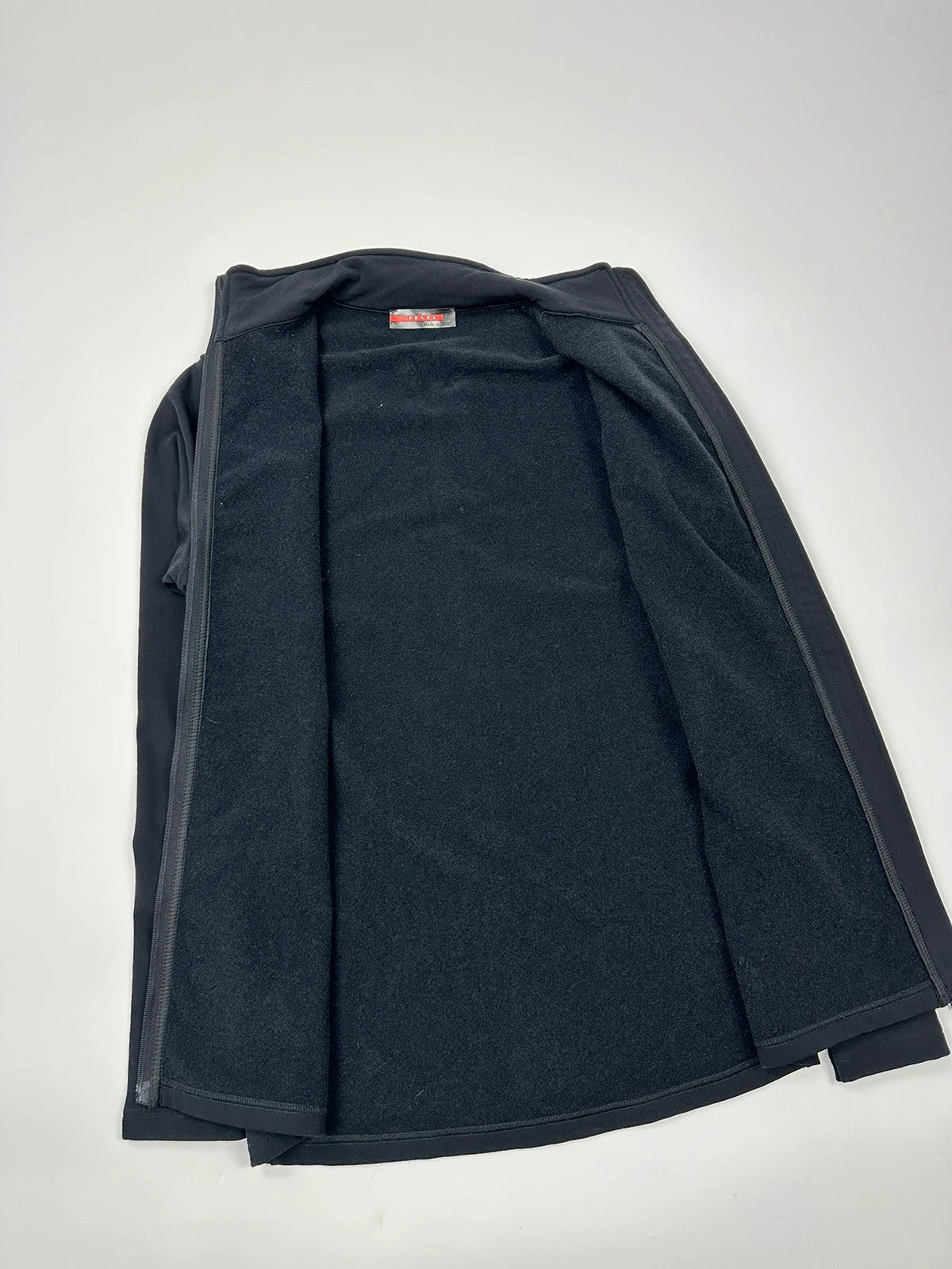 Prada black zip-up jacket featuring fleece material and iconic logo detail.