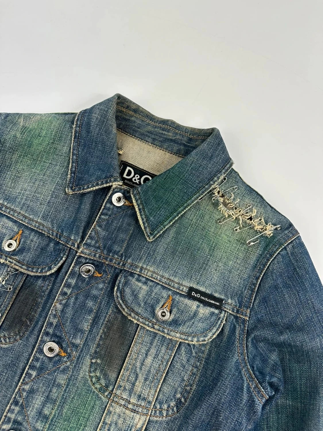 Dolce & Gabbana blue distressed denim jacket with painted details and pins.