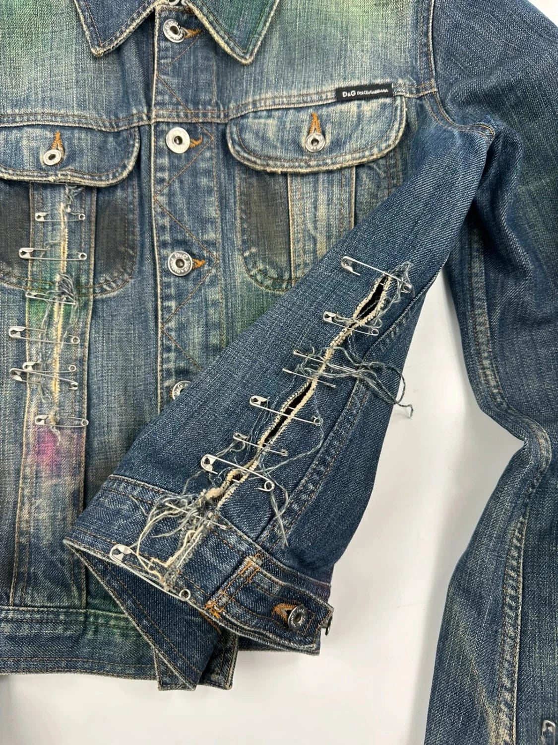 Dolce & Gabbana blue distressed denim jacket with painted details and pins.