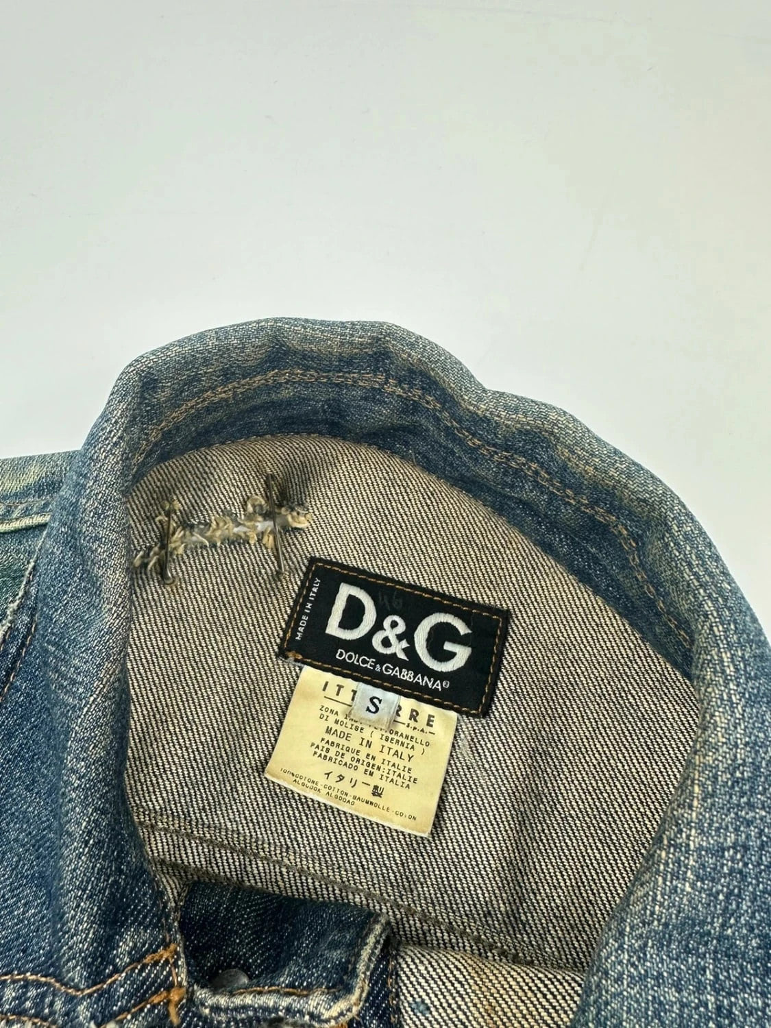 Dolce & Gabbana blue distressed denim jacket with painted details and pins.