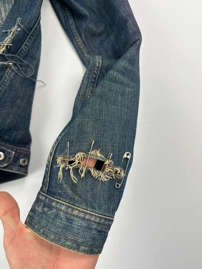 Dolce & Gabbana blue distressed denim jacket with painted details and pins.