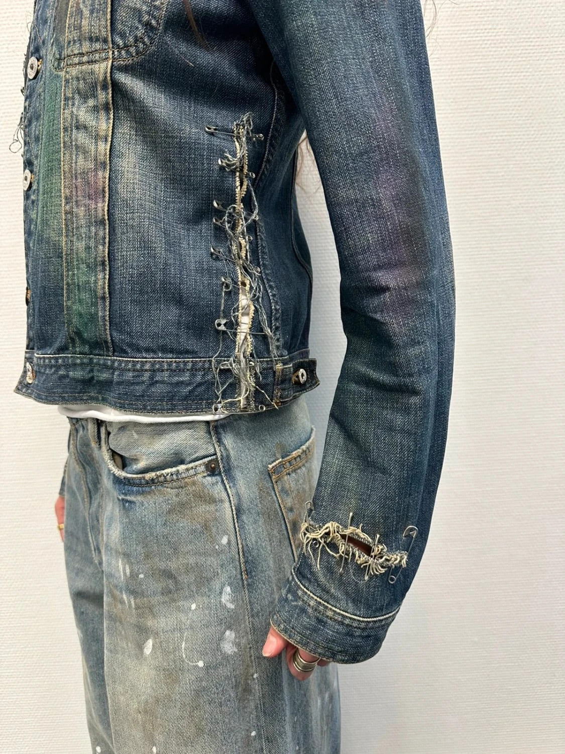 Dolce & Gabbana blue distressed denim jacket with painted details and pins.