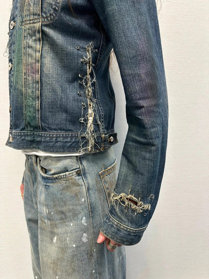 Dolce & Gabbana blue distressed denim jacket with painted details and pins.