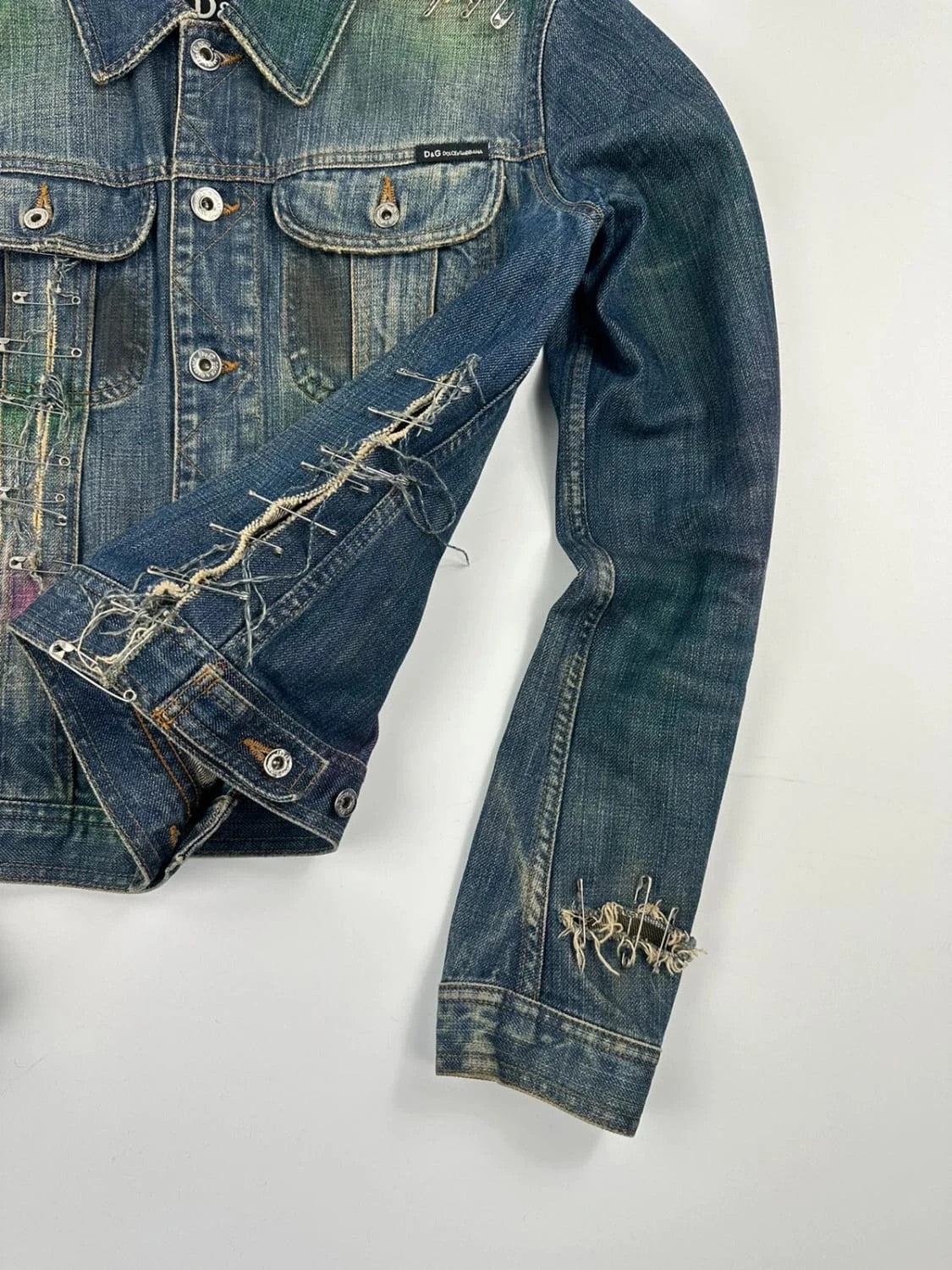 Dolce & Gabbana blue distressed denim jacket with painted details and pins.