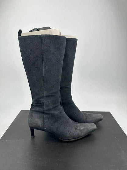 Gucci black monogram knee-high boots with pointed toe and logo pattern.