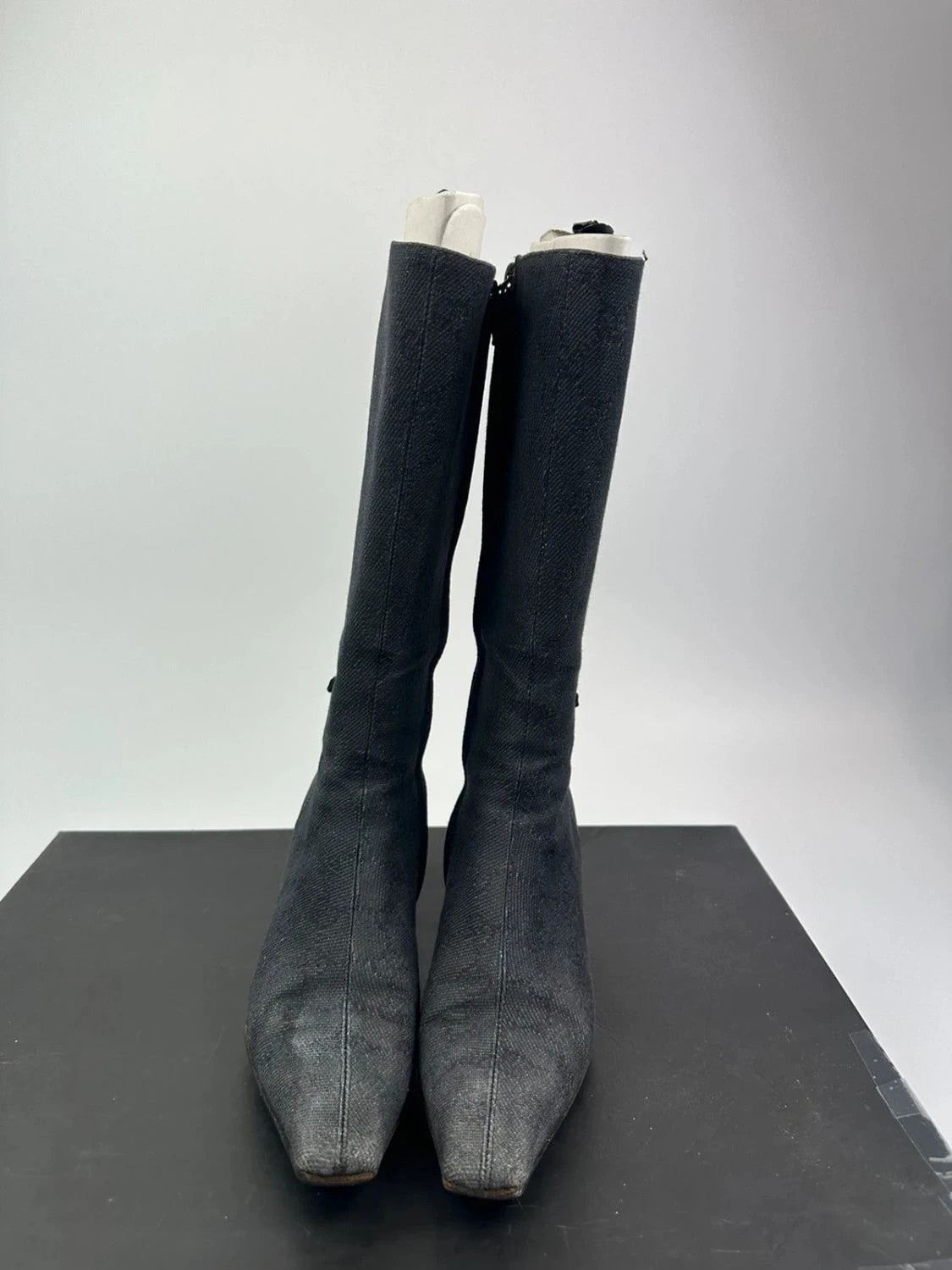 Gucci black monogram knee-high boots with pointed toe and logo pattern.