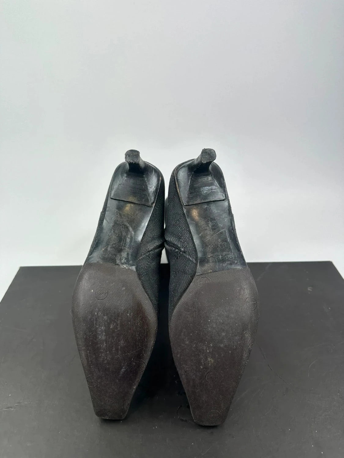 Gucci black monogram knee-high boots with pointed toe and logo pattern.