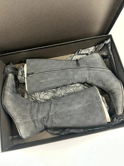Gucci black monogram knee-high boots with pointed toe and logo pattern.