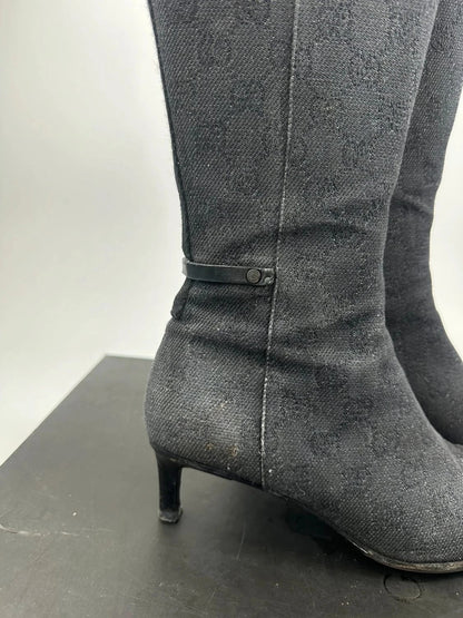 Gucci black monogram knee-high boots with pointed toe and logo pattern.