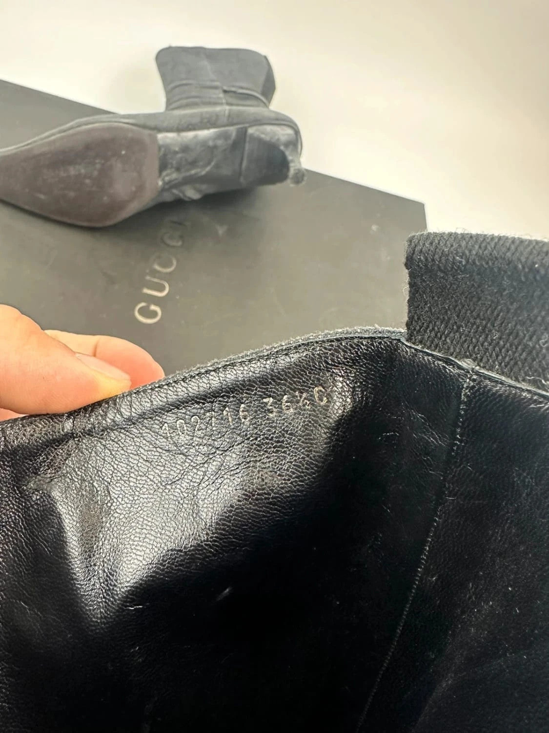 Gucci black monogram knee-high boots with pointed toe and logo pattern.