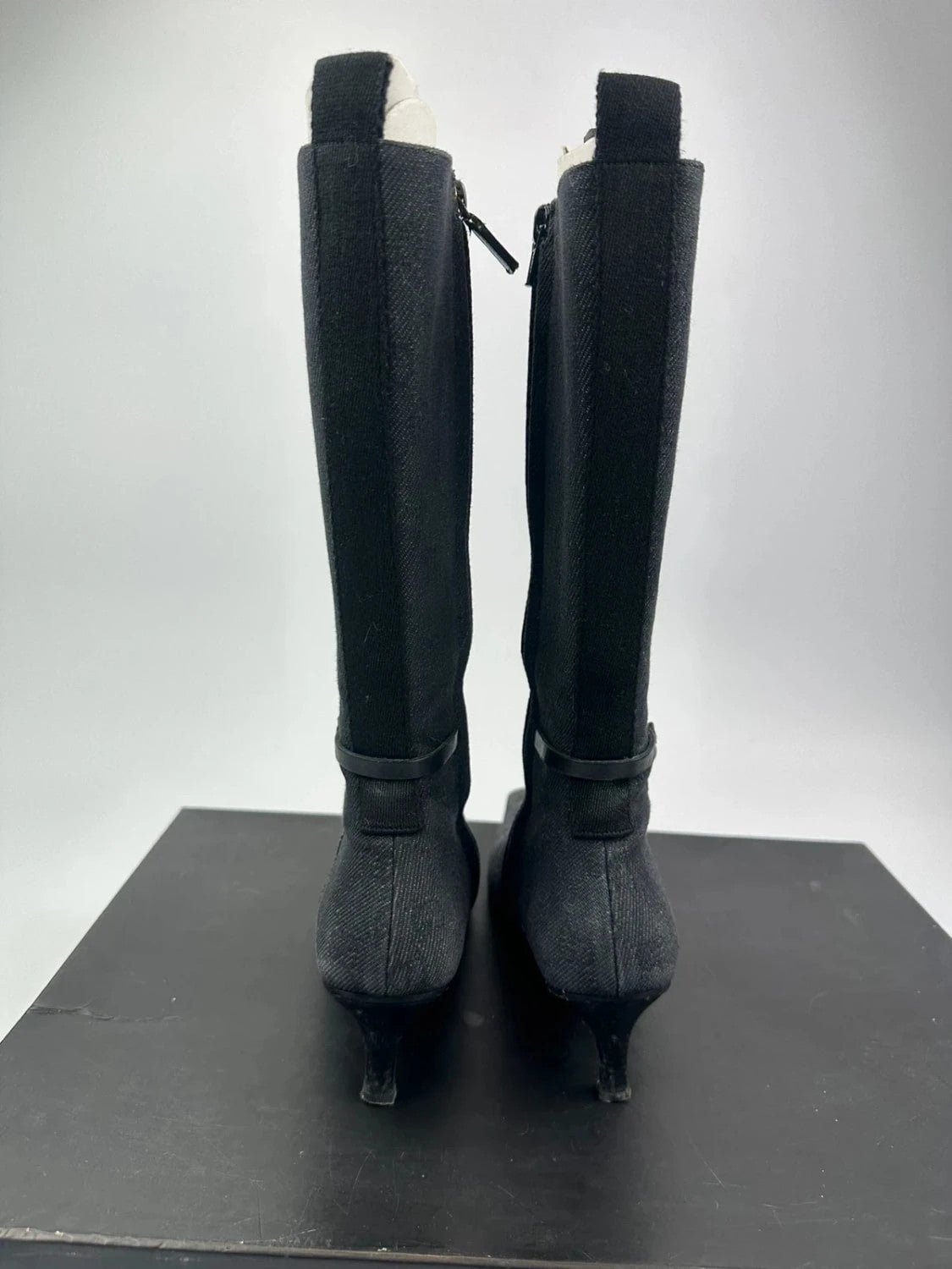 Gucci black monogram knee-high boots with pointed toe and logo pattern.